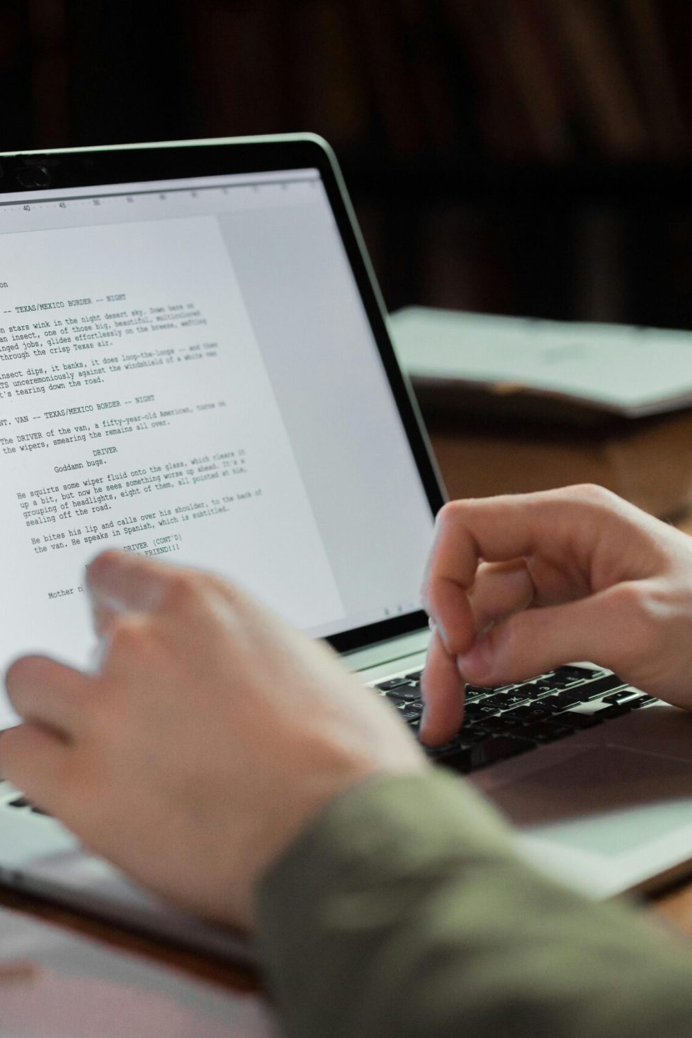 A person typing on a laptop in a cozy workspace with books around. Perfect for writing and technology themes.